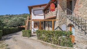 Un edificio de piedra con balcón de madera y un letrero rojo que indica un establecimiento histórico.