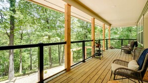 Puinen terassi, jossa on rottinkituoleja ja pöytä, ja jolta avautuu näkymä metsäiselle alueelle.