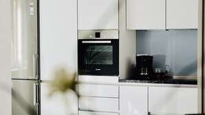 Una cucina moderna con frigorifero in acciaio inossidabile, forno Bosch e macchina da caffè sul piano di lavoro.