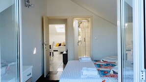 Ein Hotelzimmer mit Bett, Nachttisch, Schrank und einem durchgehenden Tür sichtbar liegenden Badezimmer.