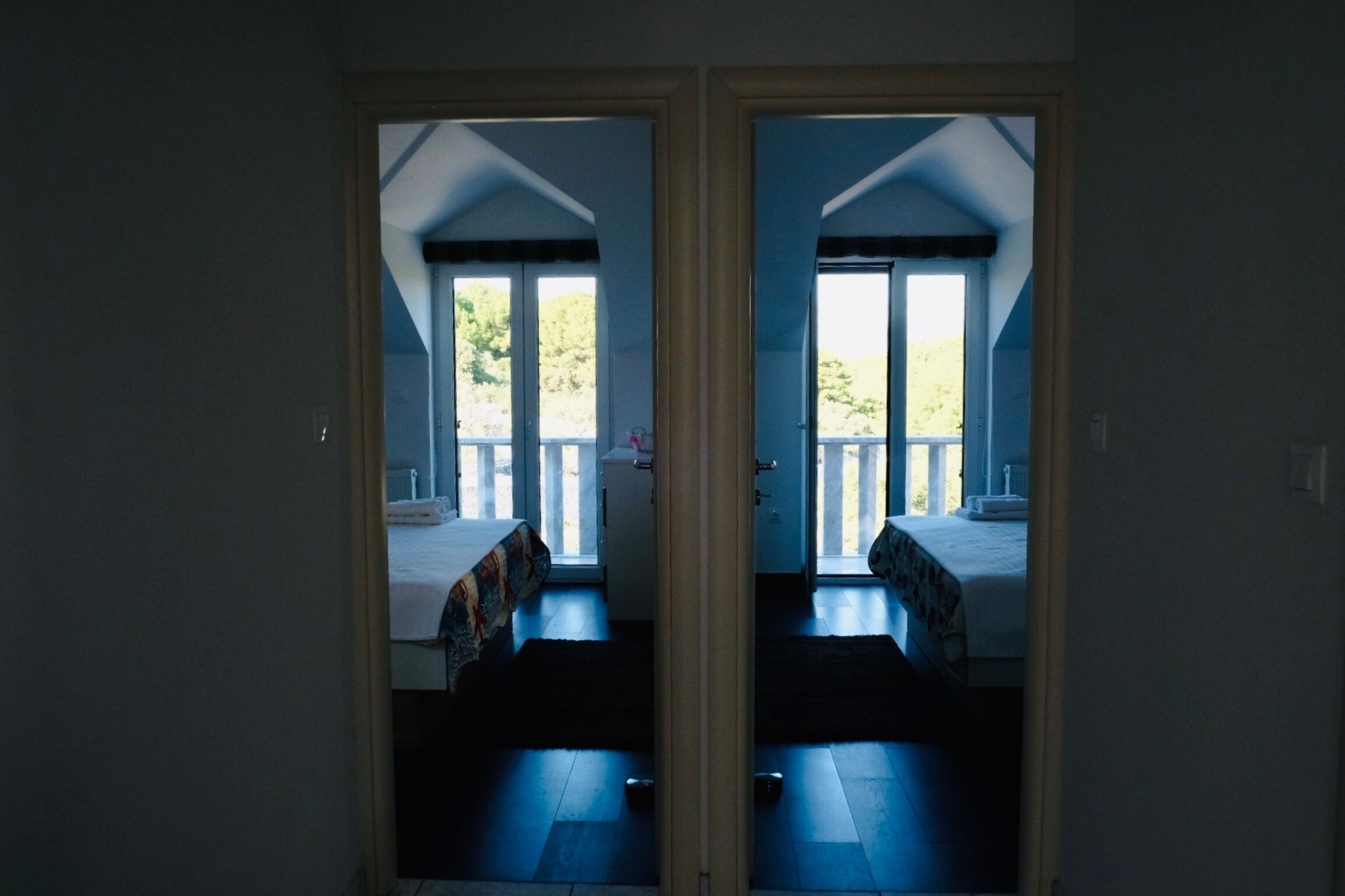 Ein Zimmer mit zwei Betten, einem Balkon und Blick ins Grüne.