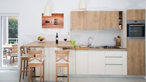 A modern kitchen with wooden cabinets, a central island with chairs, a sink, and a stove.