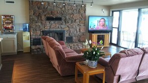 Ein Wohnzimmer mit Kamin aus Stein, einem Fernseher und einem Wasserspender.