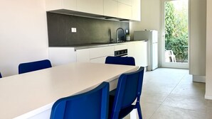 A modern kitchen with white cabinets, a black countertop, and a dining area with blue chairs. - N081 - Numana, villa with garden (Numana)