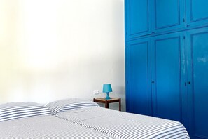 Une chambre à coucher avec un lit, une table de chevet, une lampe et des armoires bleues.