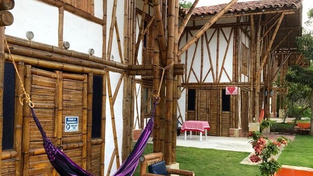 A traditional wooden building with a tiled patio, a hammock, and outdoor seating. - Hotel La Montoya (Curiti)