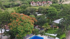 A swimming pool surrounded by lush greenery and a hillside with buildings in the background. - Hotel La Montoya (Curiti)
