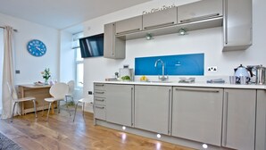 Eine moderne Küche mit grauen Schränken, einer blauen Spritzschutzwand und einem integrierten Fernseher.