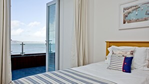 Ein Hotelzimmer mit Bett, Meerblick und einem Gemälde an der Wand.