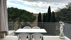 A terrace with a table and chairs, a statue, and a view of trees and hills. - M213 - Marcelli, three-room apartment with large panoramic terrace (Marcelli)