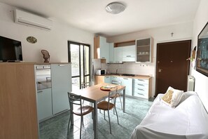 A compact kitchen with a dining table, chairs, and a sofa.