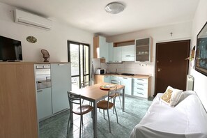 A compact kitchen with a dining table, chairs, and a sofa.