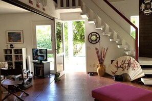 Ein Wohnzimmer mit Fernseher, Ventilator und einer Treppe zu einer weiteren Ebene.