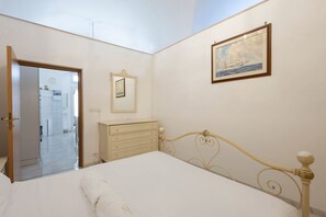A bedroom with a bed, a dresser, a mirror, and a painting on the wall.