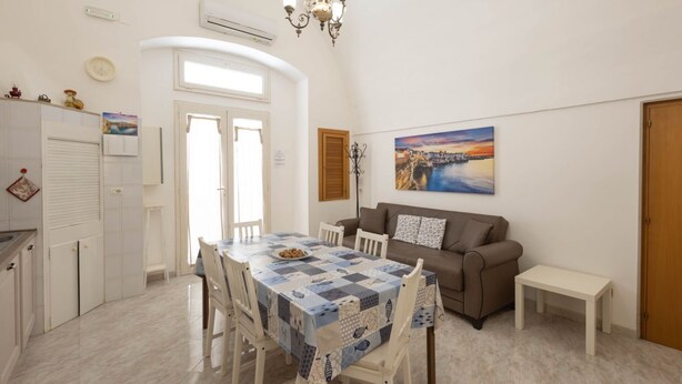 A dining area with a table set for four, a sofa, and a painting on the wall. - WePuglia - Donna Lisa (Polignano a Mare)