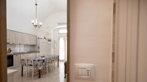 A kitchen with white cabinets, a dining table with chairs, and a chandelier. - WePuglia - Donna Lisa (Polignano a Mare)