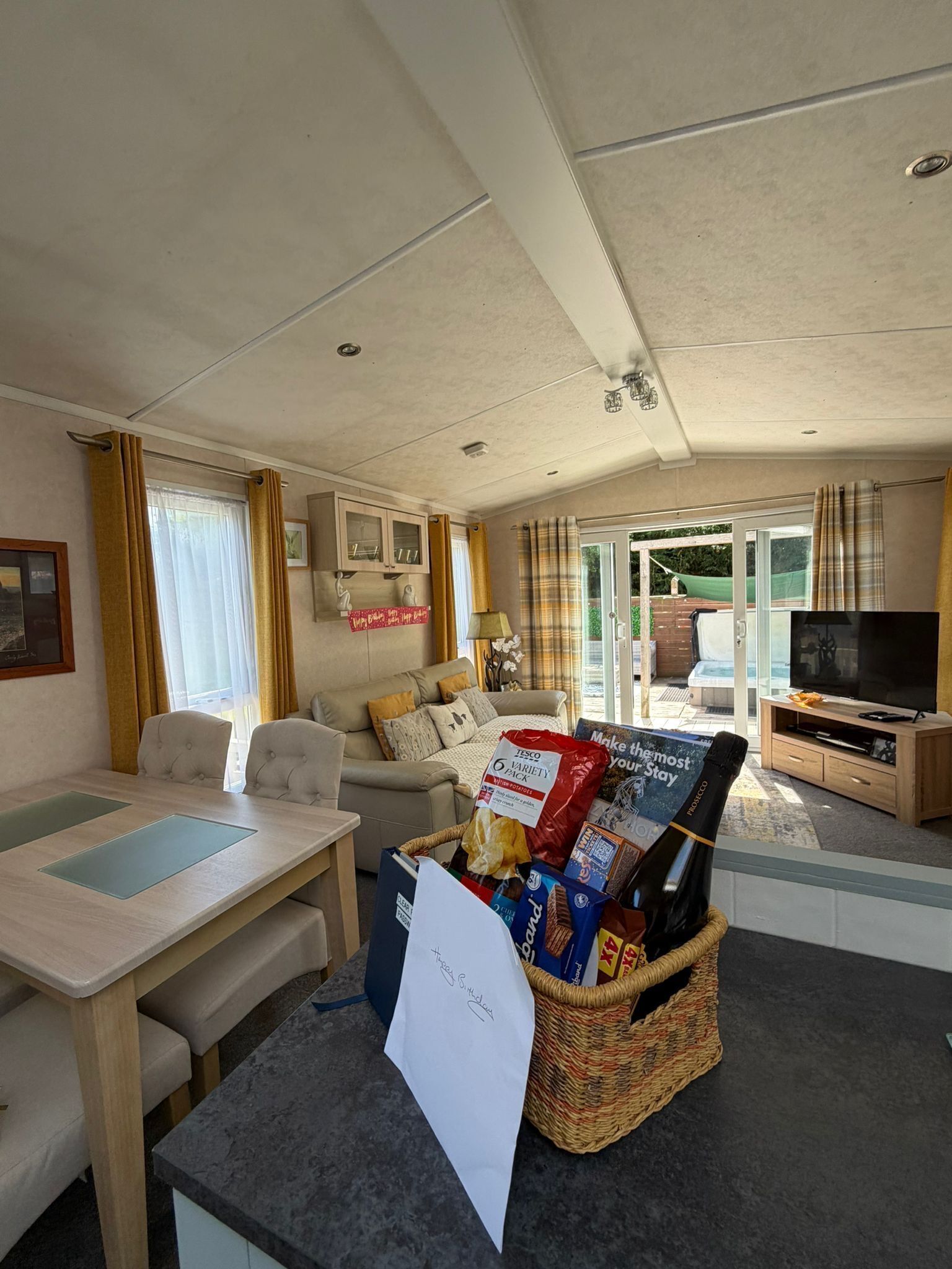 A furnished living room with a sofa, a television, a table, and a basket of snacks.