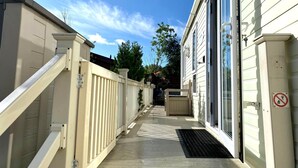A narrow pathway leading to a building with a white exterior, a gated entrance, and a no-smoking sign.