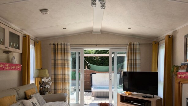 A living room with a sofa, TV, and a glass door leading to an outdoor area.