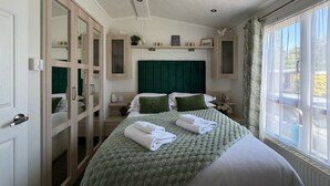 A bedroom with a bed, a wardrobe, a nightstand, a window, and a view of the outdoors.
