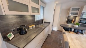 Una cocina moderna con encimeras oscuras, armarios blancos y una isla central.