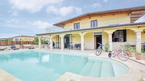 Ein Poolbereich mit überdachter Terrasse, Sitzgelegenheiten im Freien und Fahrrädern.