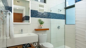 A modern bathroom with a glass shower enclosure, a white sink, and a toilet. - The Honeymoon Suite with Private Hot Tub (St. John)