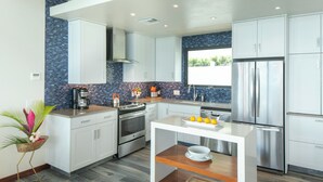 A modern kitchen with white cabinets, a stainless steel refrigerator, and a wooden island with a bowl and lemons. - The Honeymoon Suite with Private Hot Tub (St. John)
