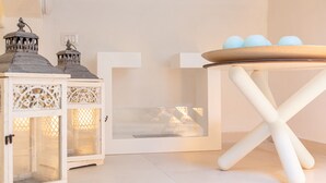 A white table with a tray holding three blue eggs, a white cabinet with intricate cut-out designs, and a white door with a small window.