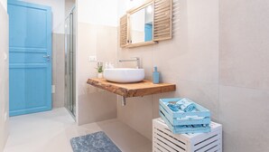 A bathroom with a wooden vanity, a white sink, a mirror, and a blue door.