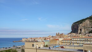 Un paysage urbain côtier avec des bâtiments, une falaise imposante et un ciel bleu dégagé.