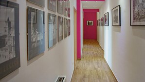 Un couloir avec des tableaux encadrés accrochés aux murs et un mur d’accent de couleur rose.