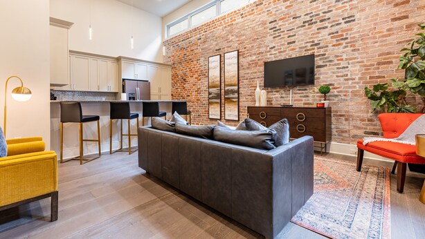Un espace de vie moderne avec un canapé gris, des chaises noires, un fauteuil jaune et une chaise rouge.