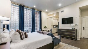 Une chambre d’hôtel moderne équipée d’un grand lit, d’un bureau, d’une télévision à écran plat et d’une kitchenette.