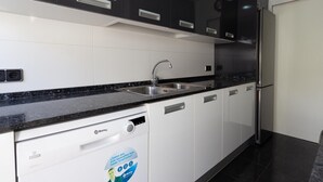 A modern kitchen with black cabinets, white countertops, and a built-in dishwasher. - INNOUTHOME GARDEN, SWIMING-POOL,BEACH AT 150M,BBQ, AC AND WIFI_VIRGEN CINTA II (L'Ametlla de Mar)