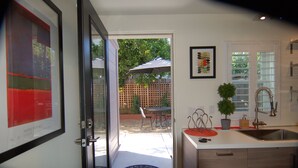 A modern kitchen with a built-in sink, a dining area with a table and chairs, and a door leading to a patio with an umbrella. - Contemporary Flat w/Gentleman's Vineyard -1 Block to Downtown Napa! Non-Hosted (Napa)
