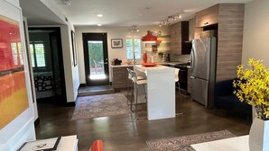 A modern kitchen with a central island, a refrigerator, and a dining area with a bench. - Contemporary Flat w/Gentleman's Vineyard -1 Block to Downtown Napa! Non-Hosted (Napa)