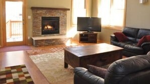 Un salon avec une cheminée, un téléviseur, un canapé en cuir et une table basse.