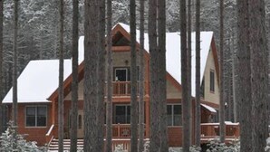 Une cabane avec une façade en bois, de nombreuses fenêtres et un balcon.