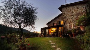 Une maison en pierre avec un patio couvert, une pelouse et des plantes en pot.