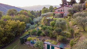 Une maison en pierre avec un jardin, une pergola et un petit abri de jardin.