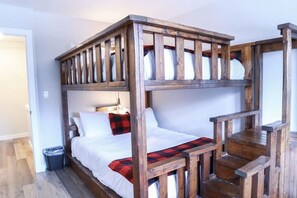 Un lit superposé avec une structure en bois et du linge de lit blanc.