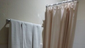 A bathroom with a toilet, a sink, and a shower curtain. - Hotel San Jose (Metapan)