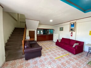 A hotel lobby with a staircase, a reception desk, a red sofa, and a tiled floor. - Hotel San Jose (Metapan)