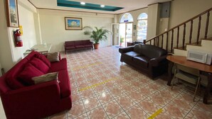 A spacious lobby with a red sofa, a brown sofa, a potted plant, and a staircase. - Hotel San Jose (Metapan)
