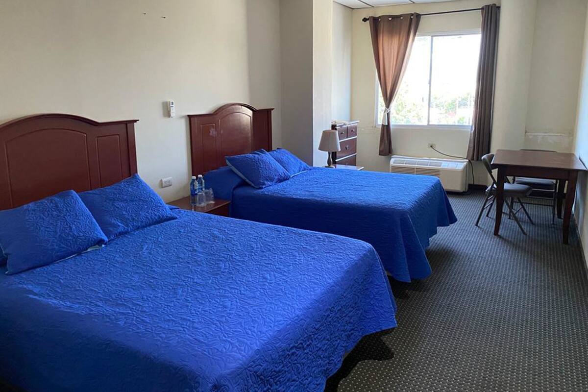 A hotel room with two beds, a desk, and a chair.