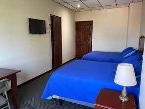 A hotel room with two beds, a desk, a chair, a TV, and a lamp. - Hotel San Jose (Metapan)