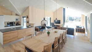 Een ruime keuken met een groot schiereiland, moderne apparatuur en een eethoek met houten meubels.