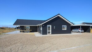Een modern herenhuis met twee verdiepingen, een donkere gevel, een schuin dak en een garage.
