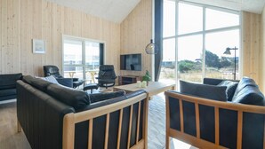 Een moderne woonkamer met houten wanden, een groot raam, een televisie en leren banken.